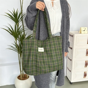 Détail du sac cabas en laine à carreaux verts avec étiquette montrant la texture du tissu
