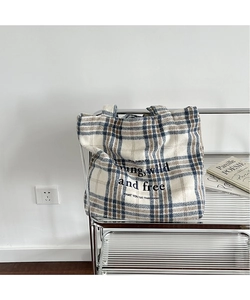 Detail of blue and brown plaid tote bag with embroidery on a silver metal cart