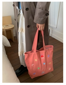 Detailed embroidery of jellyfish and sea shells on a pink canvas tote bag surface