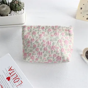 Detailed view of floral canvas lipstick pouch with brand label on textured white surface