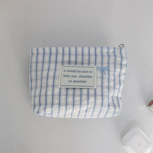 Close-up of blue and white checkered cosmetic bag with bow embroidery and metal zipper