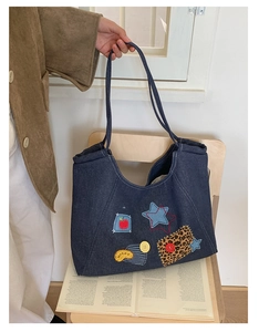Detail of vintage denim tote bag with colorful patches, star embroidery and Happy lettering
