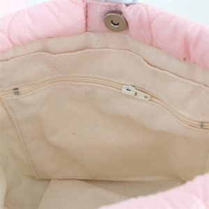 Detailed interior of pink quilted bucket bag with canvas lining and magnetic snap closure