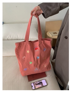 Pink canvas tote bag featuring colorful sea life embroidery like jellyfish and shells