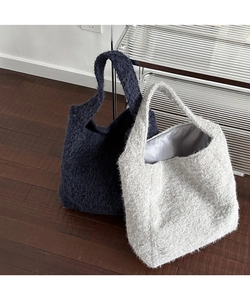 Detail of plush tote bags in navy and grey showing soft faux fur texture and roomy interior
