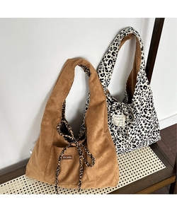 Detail of two large tote bags in corduroy and leopard print with decorative brand labels