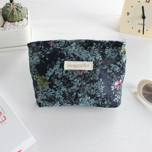 Close-up of floral pattern canvas lipstick pouch with metal zipper and brand label