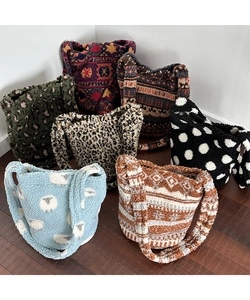 Various plush tote bags with leopard and geometric patterns displayed on wooden floor