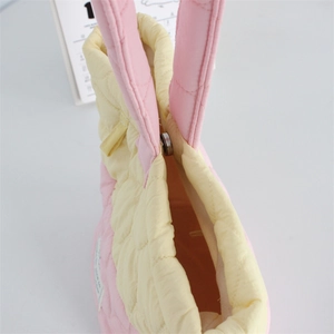 Close-up of pink and yellow quilted handbag showing silver magnetic clasp and orange lining