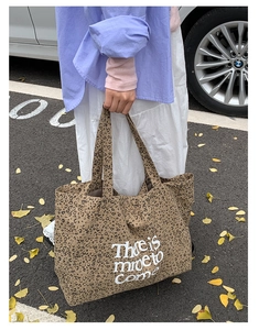 Outdoor close-up of a large leopard print canvas tote bag with white script lettering