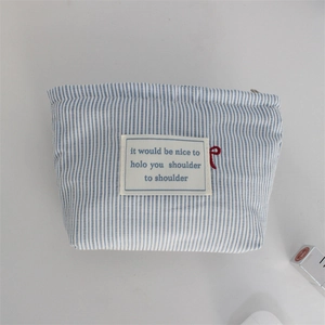 Detail view of blue striped fabric pouch with red bow embroidery and top metal zipper
