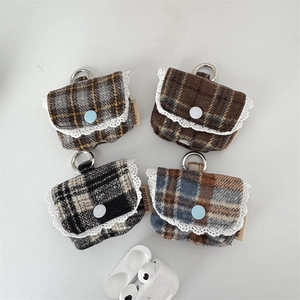Close-up of four tweed headphone cases with lace trim and metal keychains