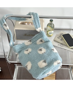Detail of plush lamb-patterned bucket bag on a modern shelf in a cozy setting