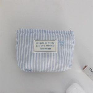 Detail of blue and white striped makeup bag with bow embroidery and metal zipper