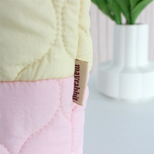 Close-up of pink and yellow quilted fabric bucket bag with mayrabbit logo tag