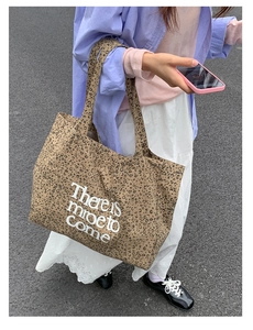 Detail of leopard print canvas tote bag with white lettering and long shoulder strap