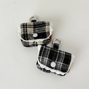 Detail of tweed earphone case with white lace trim and silver metal buckle attachment