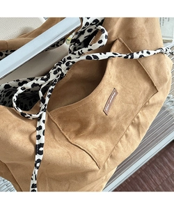 Close-up of brown suede tote bag featuring a leopard print strap and leather logo tag