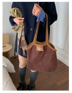 Close-up of coffee brown suede tote bag featuring Bonjour stripe label and knit handle edge