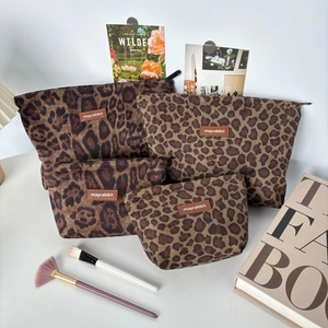 Set of four leopard print suede makeup bags in various sizes with leather logo labels