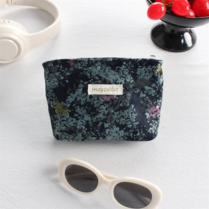 Floral canvas lipstick pouch with silver zipper and logo tag in a stylish lifestyle setting