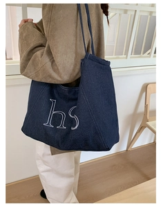 Detail of dark blue denim tote bag featuring white hs letters and contrast stitching