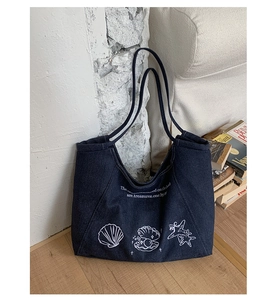 Detail of dark blue denim tote bag with white ocean themed prints and shoulder straps