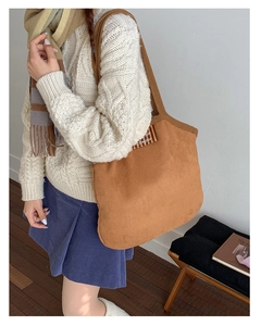 Detail of a brown faux suede tote bag with a 'Bonjour' striped tag for casual wear