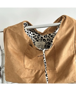 Macro detail of brown corduroy tote bag showing leopard print lining and inner label
