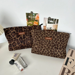Detailed close-up of two leopard print suede cosmetic bags with black zippers and leather tags