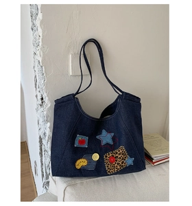 Detail of blue denim tote bag featuring star and happy patches with button accents