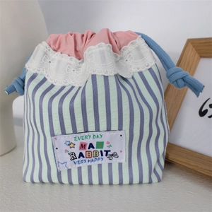 Close-up of blue striped lace storage bag with drawstring and cute rabbit patch detail