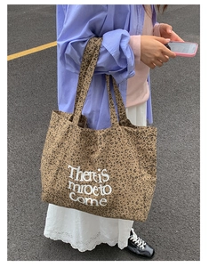 Close-up of leopard print canvas tote bag with white lettering on street background