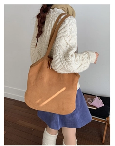 Detail of a large brown suede tote bag featuring striped webbing and a casual shoulder strap