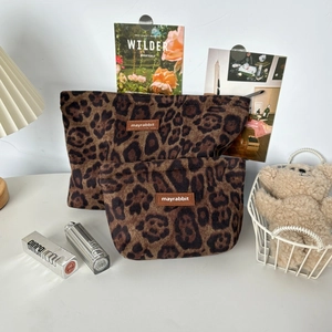 Macro shot of faux fur leopard print cosmetic bag with brown leather logo patch
