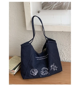 Detailed embroidery of shells and sea stars on a vintage blue denim tote bag