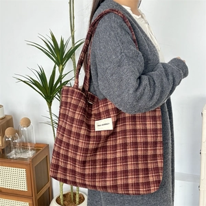 Détail du grand sac cabas à carreaux rouge-brun avec étiquette sur tissu de laine