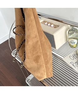 Detail of a brown faux suede tote bag with stylish leopard print straps on a shelf