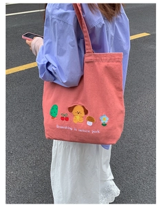 Detailed embroidery of cartoon dogs and nature motifs on pink denim tote bag