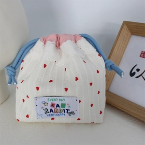 Detail of cute drawstring bag with red heart pattern, pink lace trim, and blue cord