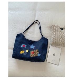 Flat lay of vintage denim tote bag with colorful patches, star and button embroidery details
