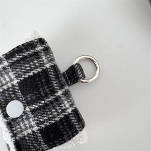 Detailed view of tweed earbud pouch with lace trim and silver metal ring clip