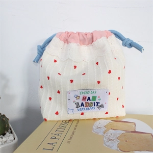 Close-up of cream drawstring storage pouch with red hearts and delicate lace trim detail