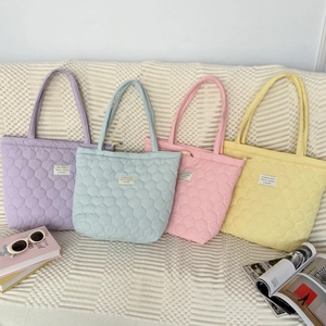 Gesteppte Tragetaschen in Pastellfarben Lavendel, Blau, Rosa und Gelb auf einem Sofa