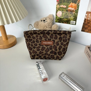 Detailed close-up of retro leopard print suede makeup bag with branded leather patch