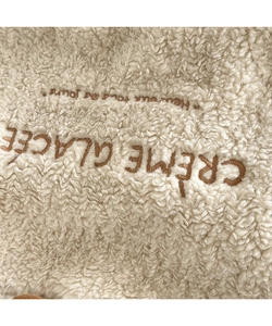 Close-up of beige faux shearling fabric featuring premium brown letter embroidery detail