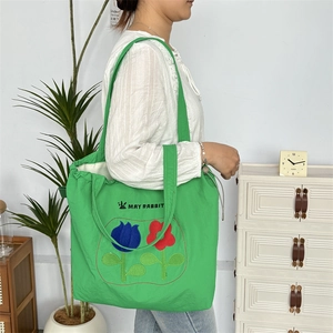 Detail der grünen Nylon-Tasche mit Kordelzug, Blumenstickerei und Logo