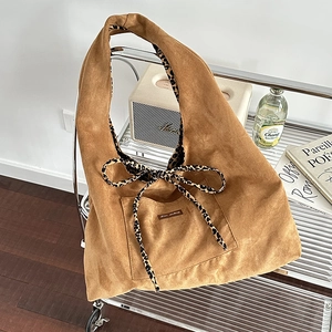 Brown suede tote bag with leopard print bow detail on a modern silver cart