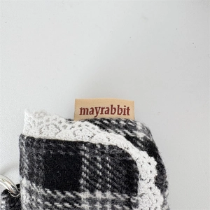Detail of checkered tweed earphone pouch with crochet lace trim and metal ring hook