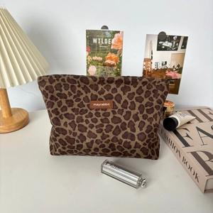 Detailed view of leopard print suede makeup bag with brown leather brand tag and zipper
